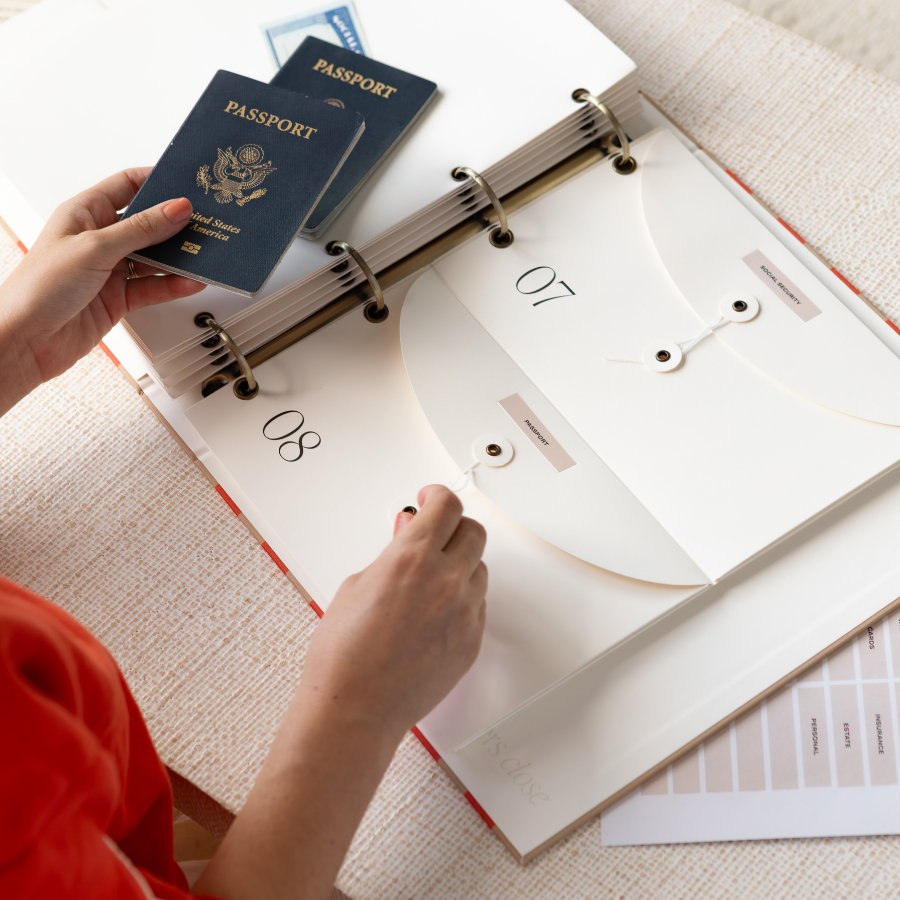 Person organizing documents including a passport in an open DailyDocs organizer binder.