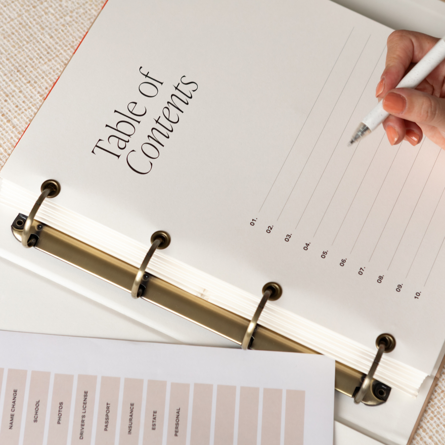 Open DailyDocs document organizer with 'Table of Contents' and a hand holding a pen on a textured surface.