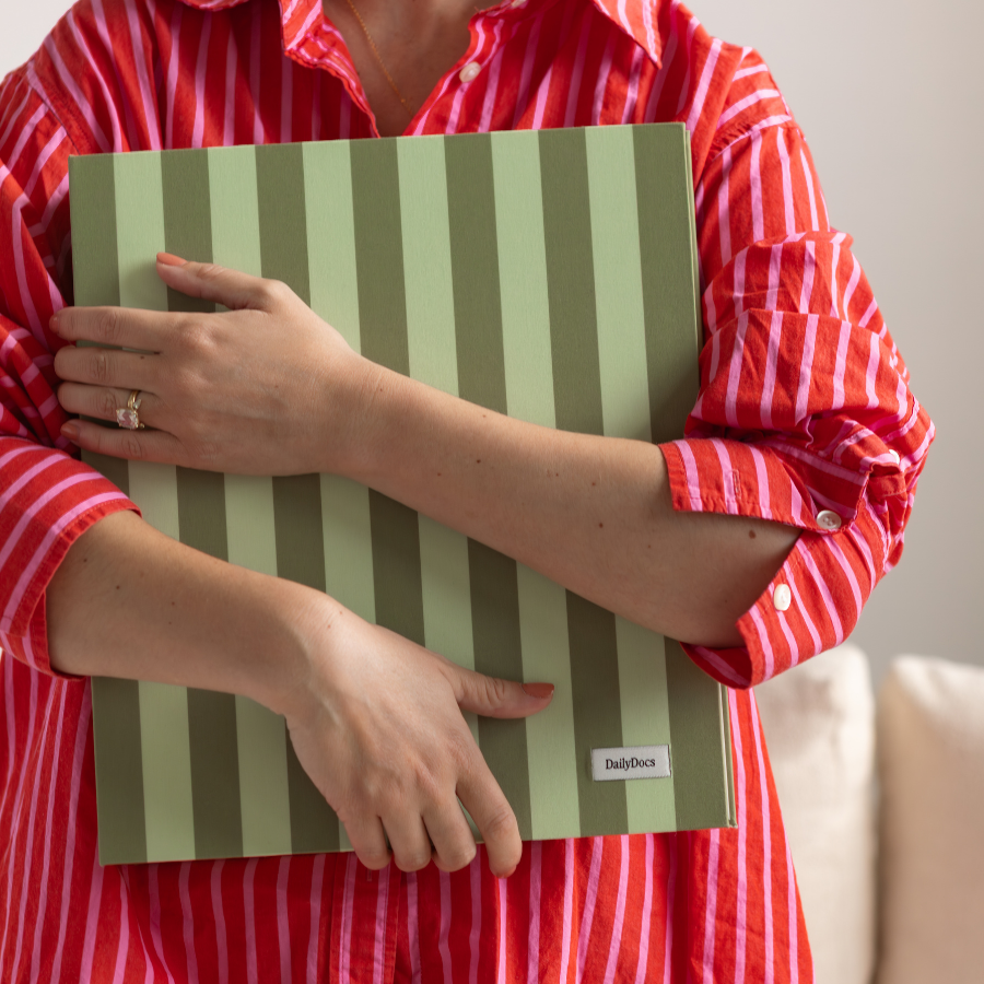 Person holding a green and beige document organizer with 'DailyDocs' branding.
