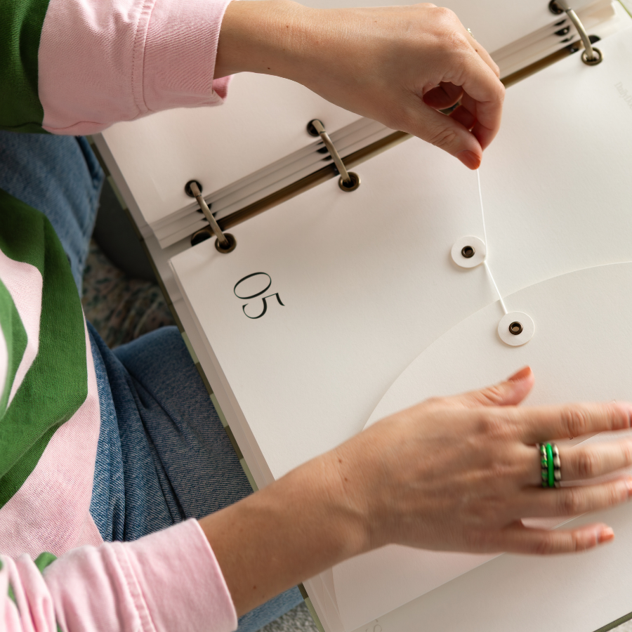 Person adjusting a ring on a white surface with a green and pink sleeve.