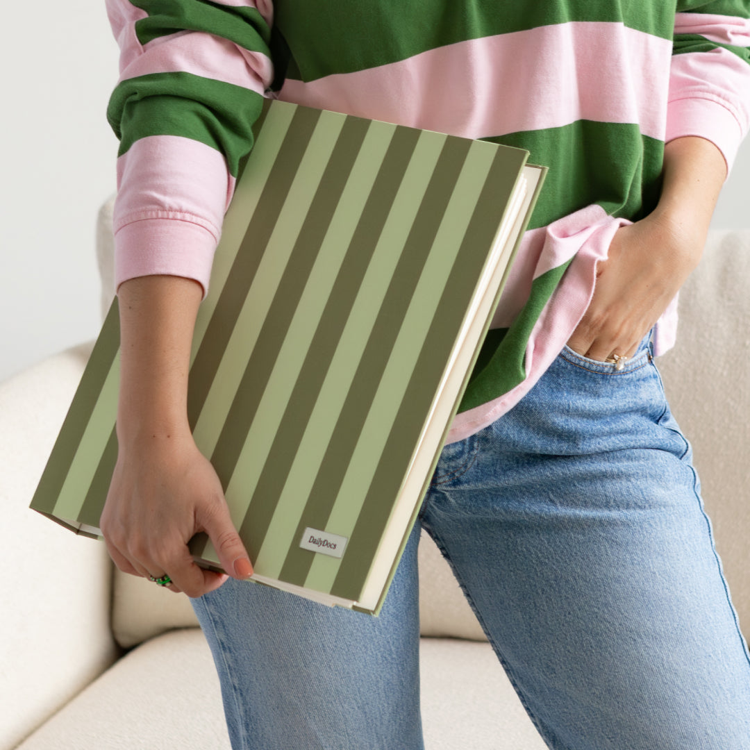 Person holding a green and white striped document organizer with a plain background