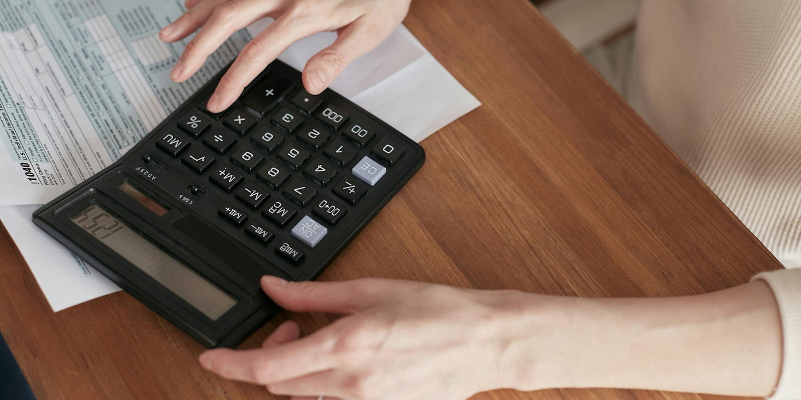 A Woman Using A Calculator For Her Tax Forms