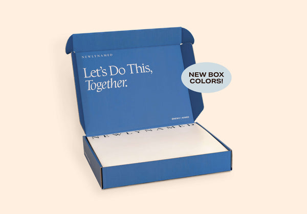 Open blue NewlyNamed Box printed name change kit with "Let's Do This, Together" inner lid text, stacked papers, and "New Box Colors" tag.