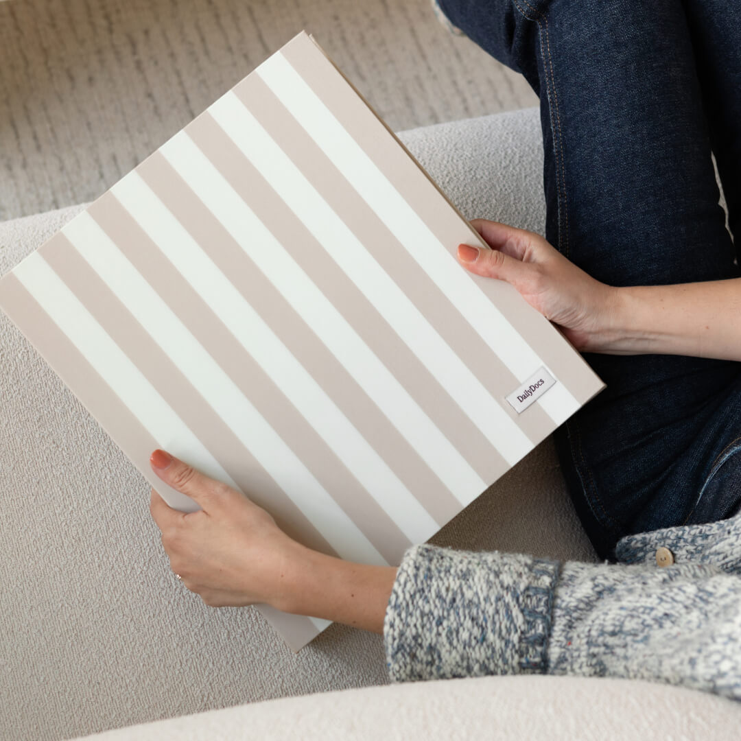 DailyDocs document organizer in Oat neutral striped design held on a sofa