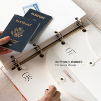 Passports being placed into a ring-bound binder with button closures.