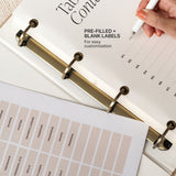 Table of contents with pre-filled and blank labels for customization, held by a hand with a pen.