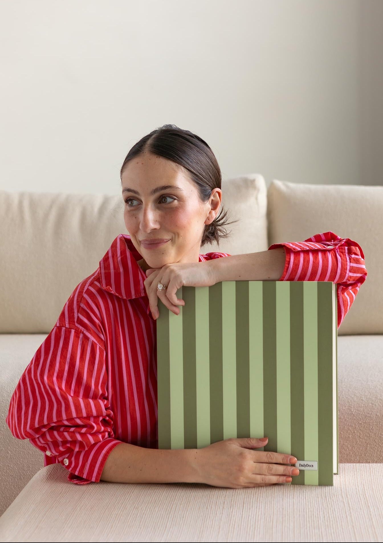 Woman holding a green striped binder on a beige couch