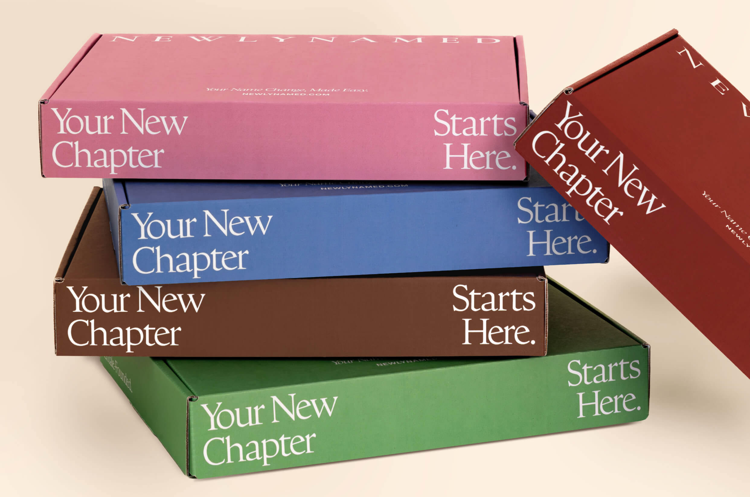 A stack of colorful NewlyNamed name change kit boxes featuring the text Your New Chapter Starts Here.
