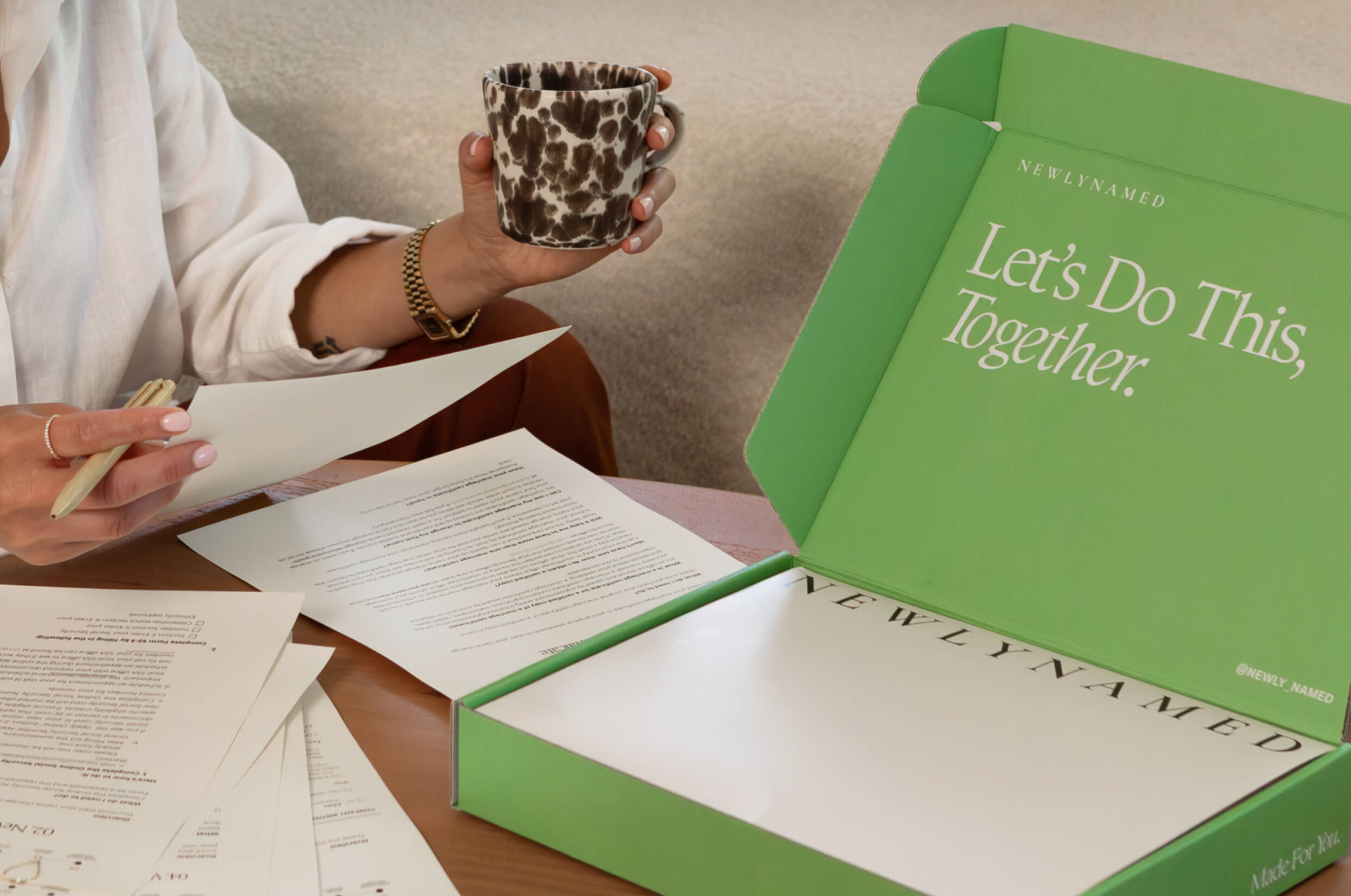 An open green NewlyNamed Box with printed name change instructions and a personalized checklist being completed at home.
