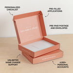Open pink NewlyNamed Box with text highlighting features on a light wooden surface.