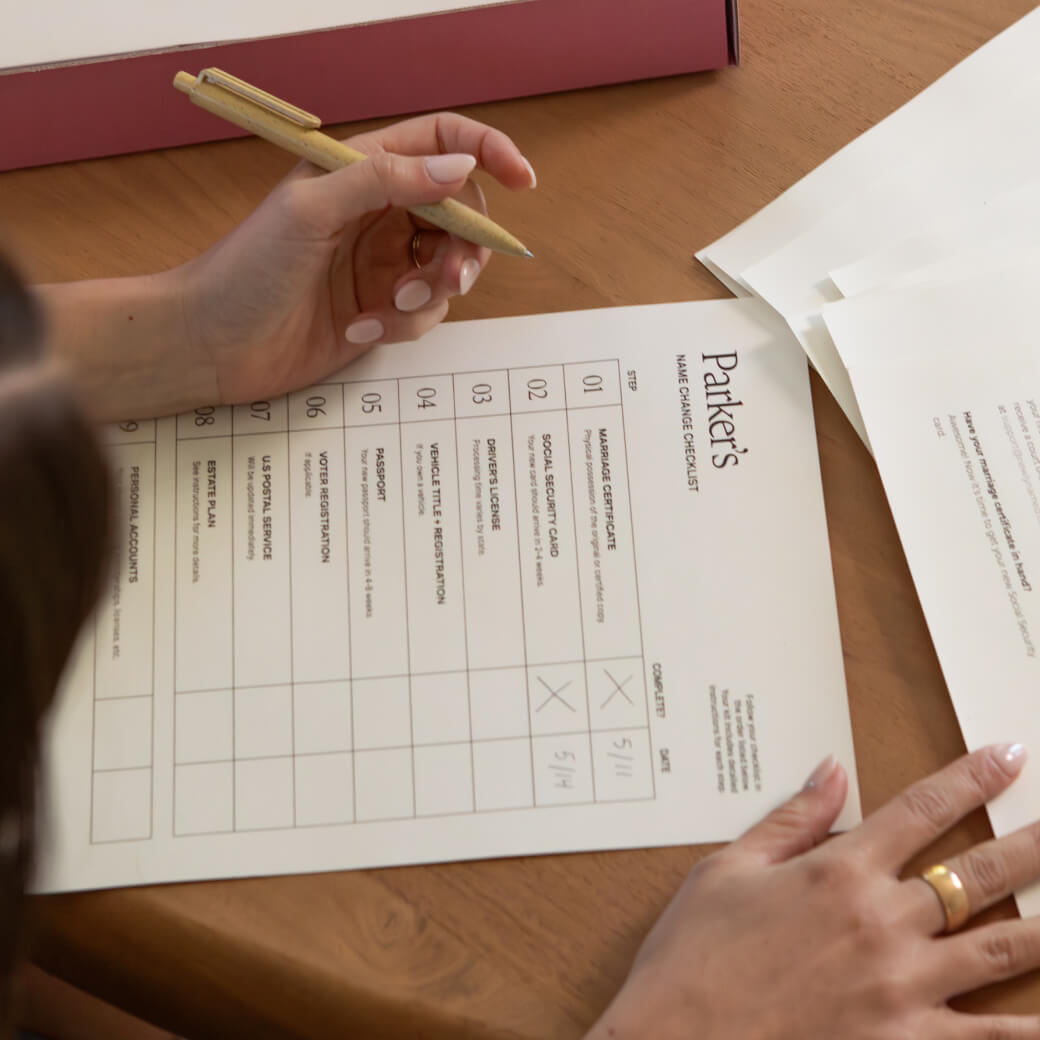 A close-up, top-down view of a person holding a tan pen, filling out a document titled 