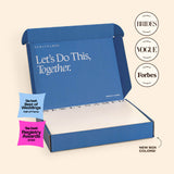 An open blue NewlyNamed Box complete marriage name change kit featuring award badges from The Knot, Brides, Vogue, and Forbes.