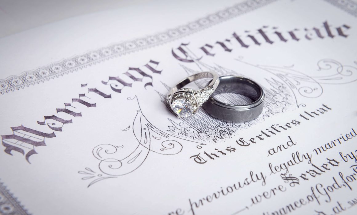 marriage certificate with bride and groom rings